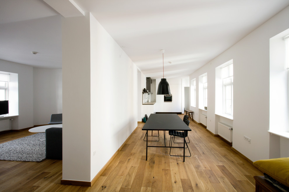 Immagine di una sala da pranzo aperta verso il soggiorno nordica di medie dimensioni con pareti bianche, pavimento in legno massello medio e nessun camino
