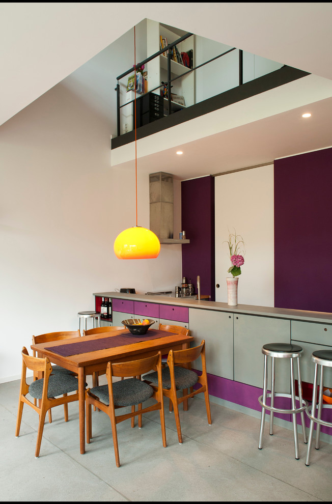 Exempel på en mellanstor modern matplats med öppen planlösning, med lila väggar och betonggolv