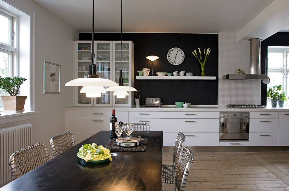 Réalisation d'une salle à manger ouverte sur la cuisine vintage avec un mur blanc et parquet clair.