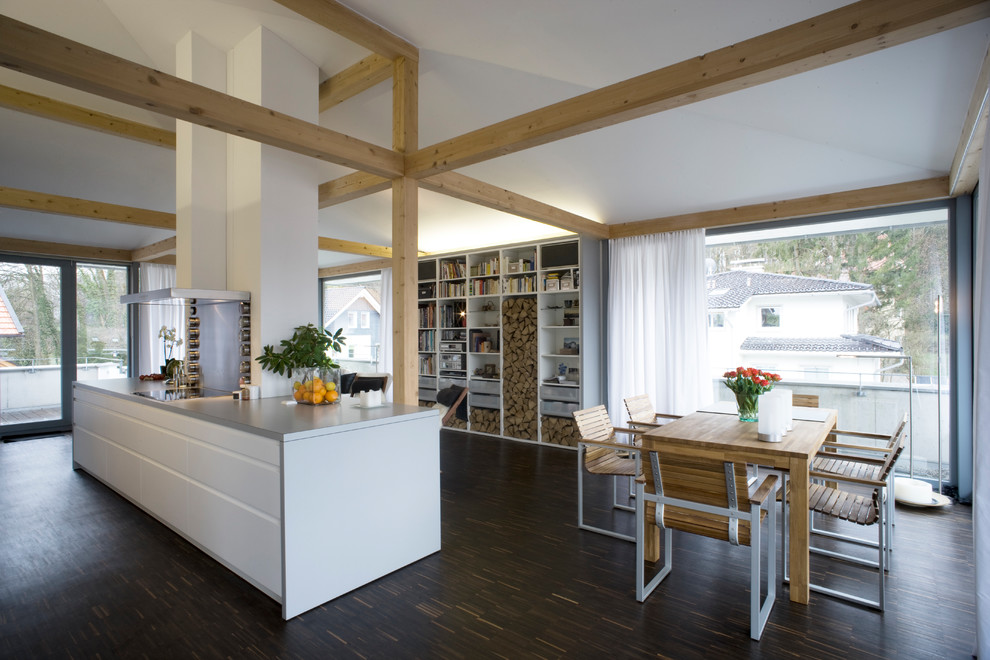 Inspiration pour une salle à manger ouverte sur le salon design avec un sol marron, un mur blanc et parquet foncé.