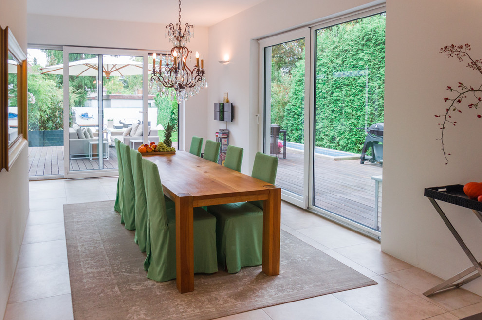 Immagine di una grande sala da pranzo aperta verso il soggiorno contemporanea con pareti bianche e pavimento in pietra calcarea