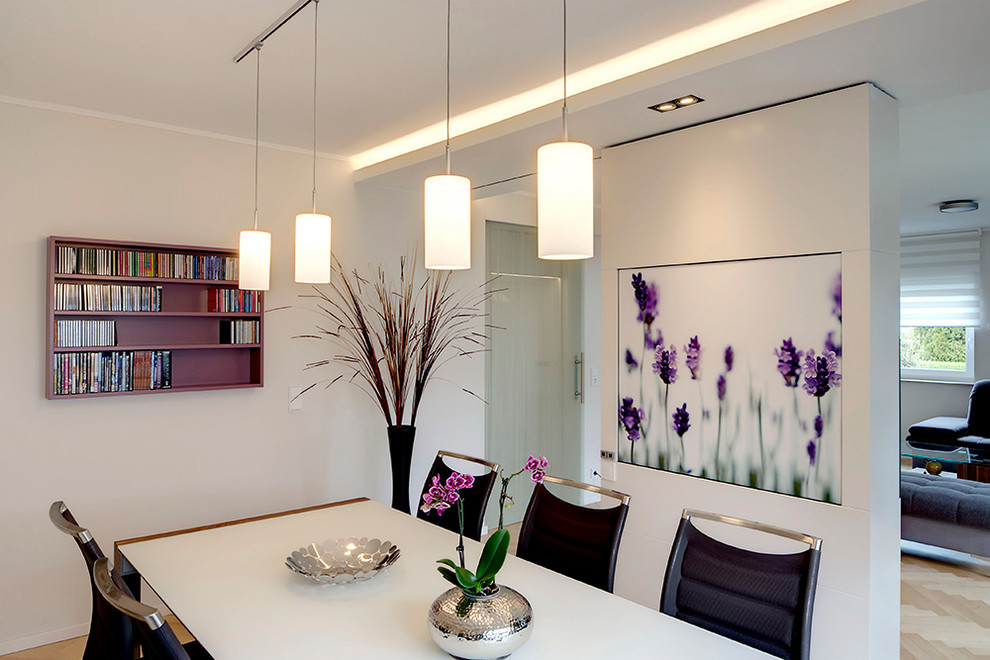 This is an example of a medium sized contemporary open plan dining room in Leipzig with white walls and light hardwood flooring.
