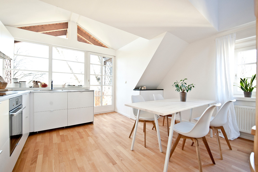 Пример оригинального дизайна: кухня-столовая в современном стиле с белыми стенами и светлым паркетным полом без камина