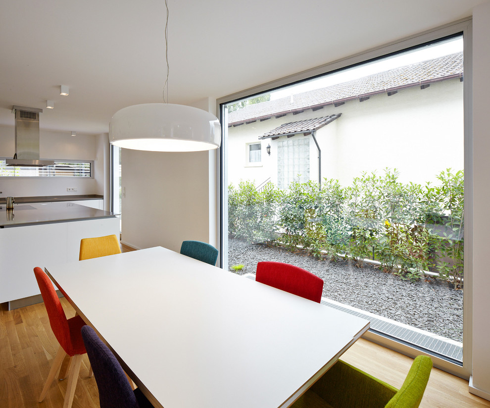 Photo of a medium sized contemporary open plan dining room in Frankfurt with white walls and light hardwood flooring.