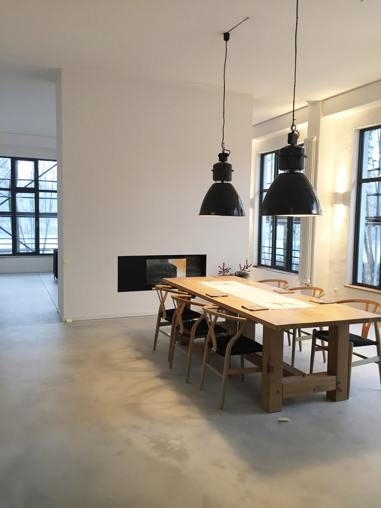 Immagine di una grande sala da pranzo aperta verso il soggiorno design con pareti bianche, camino lineare Ribbon e pavimento in cemento