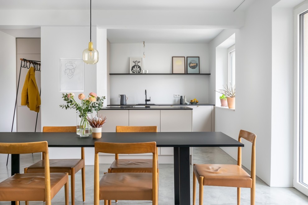 Immagine di una sala da pranzo aperta verso la cucina contemporanea con pareti bianche e pavimento grigio