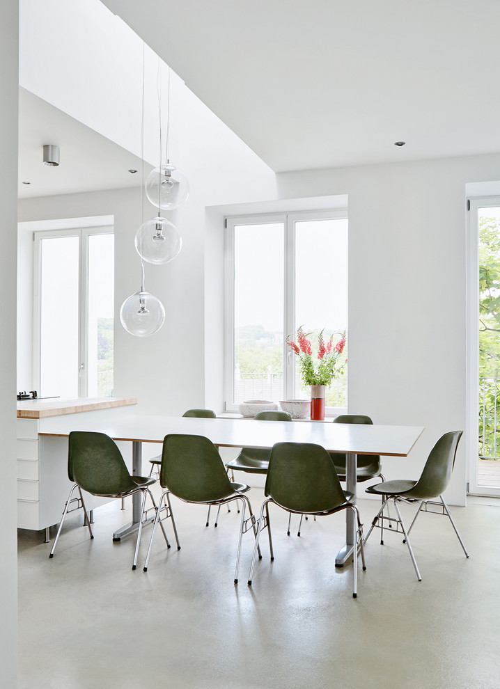 Diseño de comedor minimalista con paredes blancas y suelo de cemento