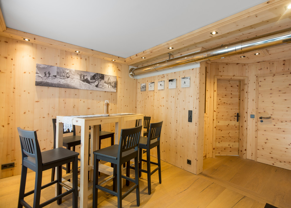 Cette image montre une salle à manger rustique de taille moyenne et fermée avec un mur beige, parquet clair, aucune cheminée et un sol marron.
