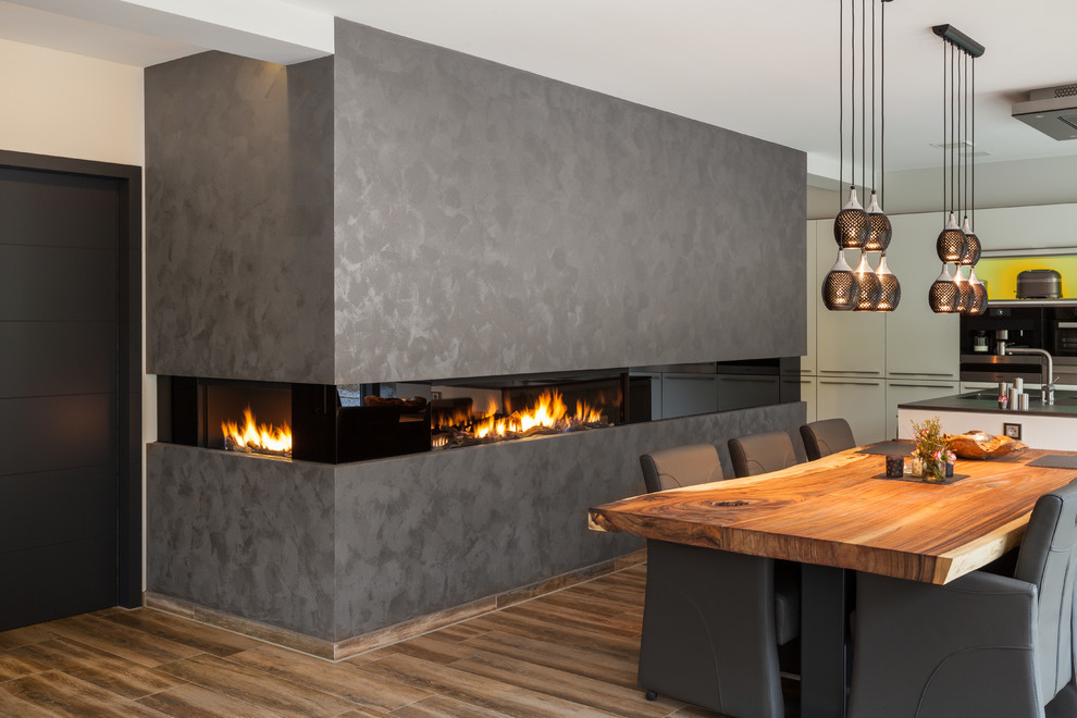 Imagen de comedor de cocina contemporáneo de tamaño medio con paredes blancas, suelo de madera oscura, chimenea lineal y marco de chimenea de yeso
