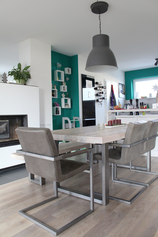 Cette photo montre une salle à manger ouverte sur la cuisine scandinave avec un mur blanc, un sol en vinyl, un sol marron et une cheminée double-face.