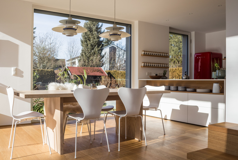Idee per una sala da pranzo aperta verso la cucina minimal con pareti bianche, pavimento in legno massello medio e pavimento marrone