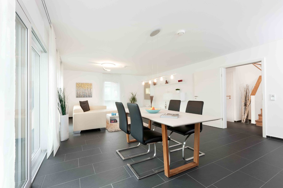 Photo of a medium sized contemporary open plan dining room in Stuttgart with white walls, ceramic flooring, no fireplace and black floors.