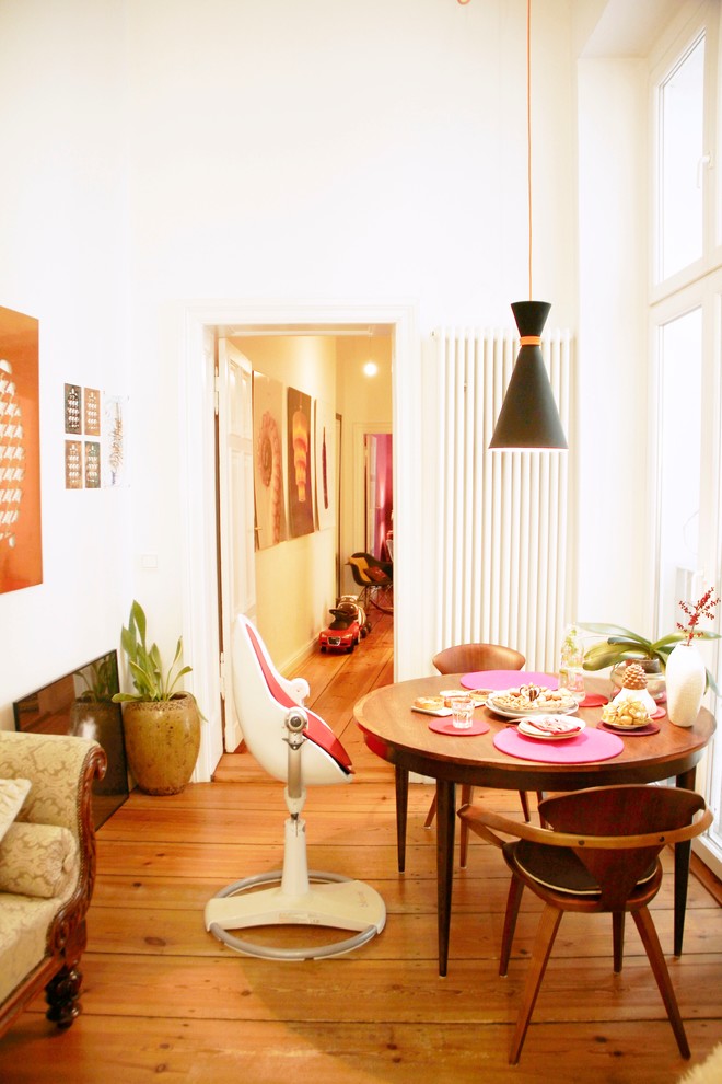 Kleines, Geschlossenes Stilmix Esszimmer ohne Kamin mit weißer Wandfarbe und braunem Holzboden in Berlin