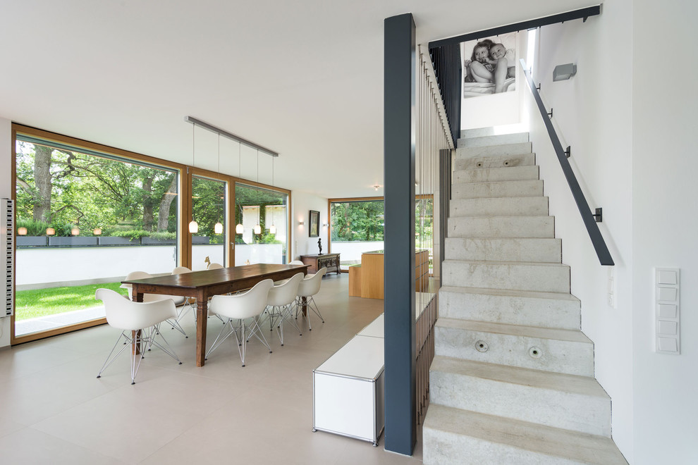 Immagine di una grande sala da pranzo aperta verso il soggiorno design con pareti bianche e pavimento in cemento