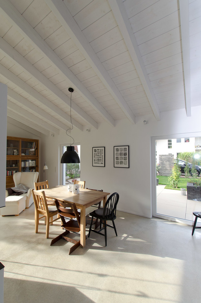 На фото: гостиная-столовая среднего размера в стиле кантри с серым полом, белыми стенами и бетонным полом без камина с