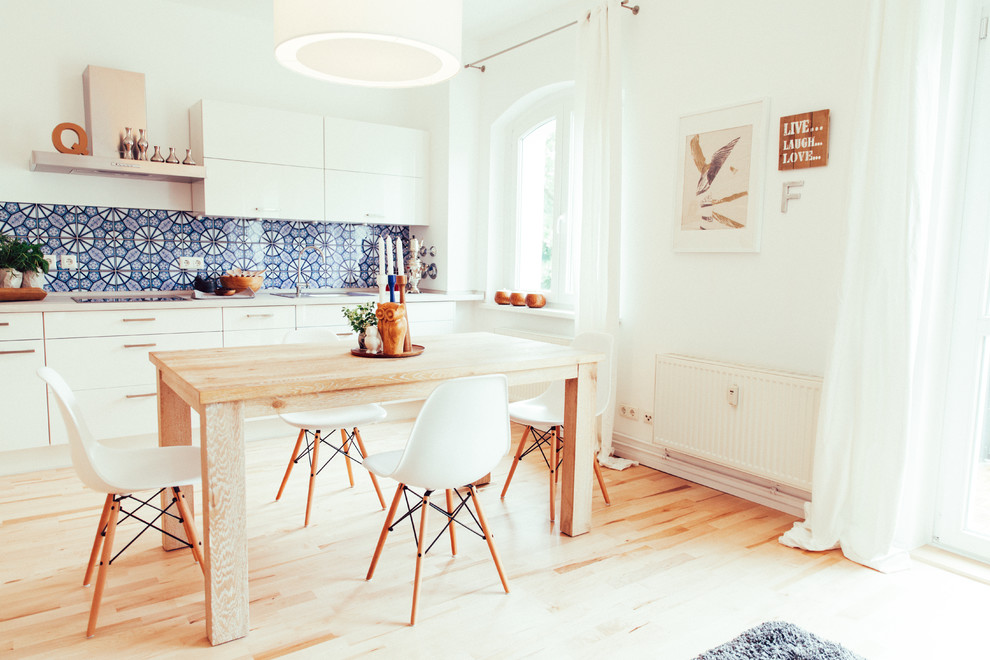 Esempio di un'ampia sala da pranzo aperta verso la cucina minimal con pareti bianche e parquet chiaro
