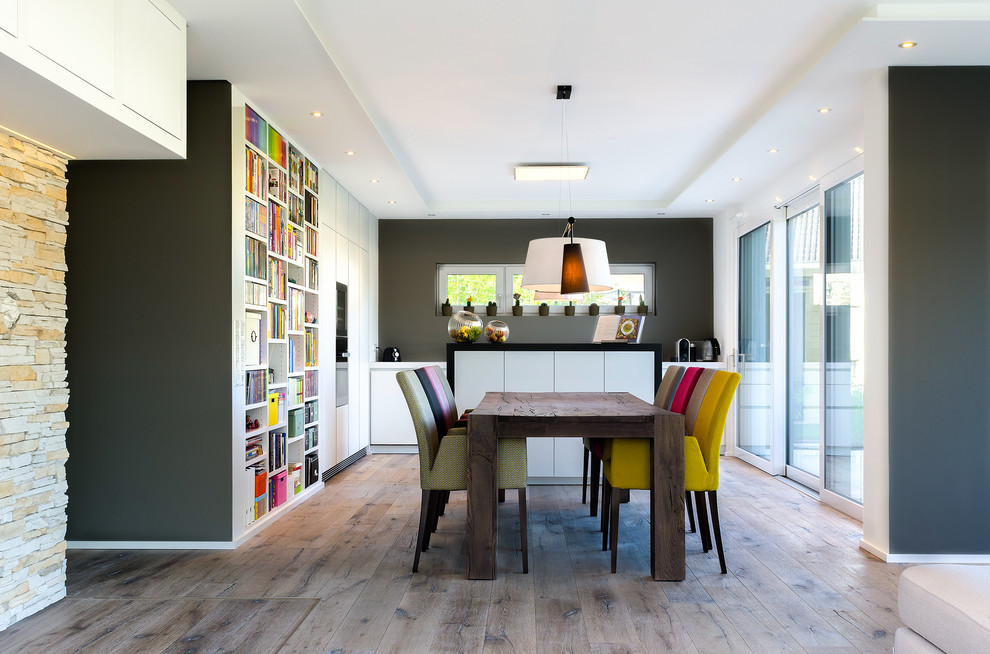 Immagine di una sala da pranzo aperta verso il soggiorno contemporanea di medie dimensioni con pareti grigie, pavimento in legno massello medio e nessun camino