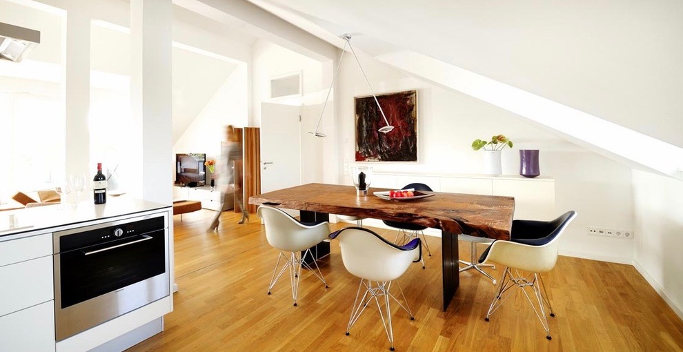 Cette photo montre une salle à manger ouverte sur le salon rétro de taille moyenne avec un mur blanc, un sol en bois brun et un sol marron.