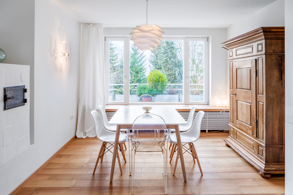 Diseño de comedor nórdico de tamaño medio abierto con paredes blancas, suelo de madera clara y estufa de leña