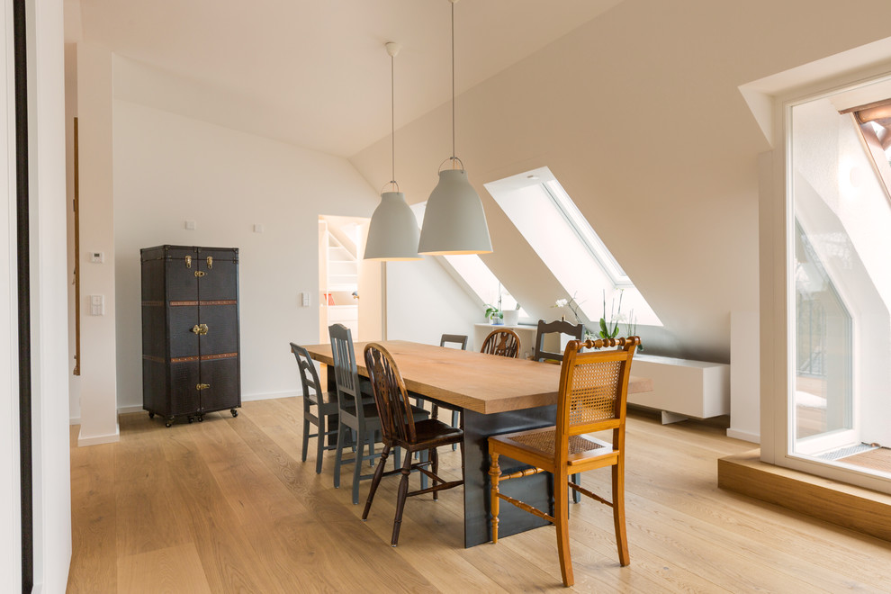 Cette photo montre une salle à manger ouverte sur le salon tendance de taille moyenne avec parquet clair, un mur blanc, aucune cheminée et un sol marron.