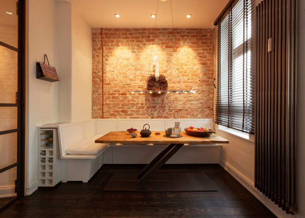 Cette image montre une très grande salle à manger ouverte sur la cuisine design avec un mur blanc, parquet foncé, aucune cheminée, un manteau de cheminée en brique et un sol marron.