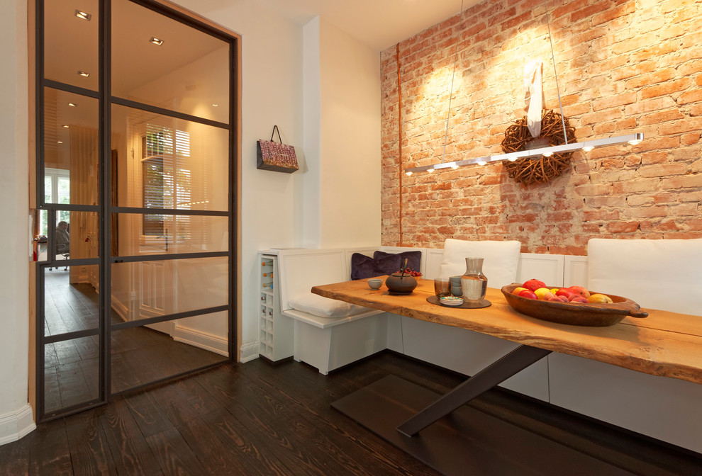 Geräumige Moderne Wohnküche ohne Kamin mit dunklem Holzboden, weißer Wandfarbe, Kaminumrandung aus Backstein und braunem Boden in Hamburg