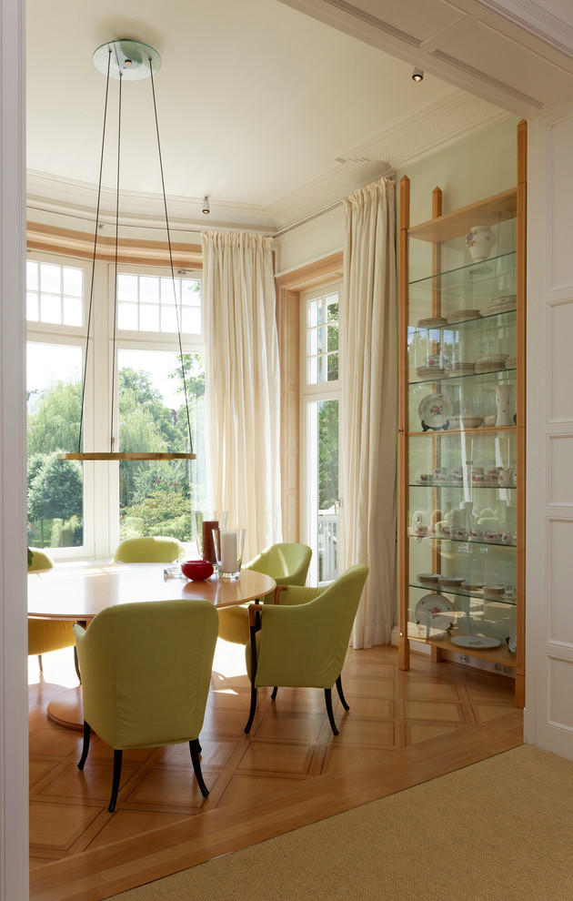 Elegant medium tone wood floor enclosed dining room photo in Hamburg with white walls