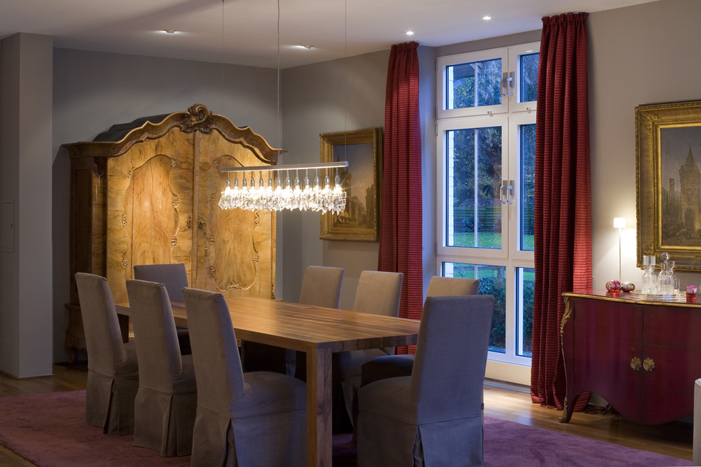 Aménagement d'une grande salle à manger classique avec un mur gris et un sol en bois brun.