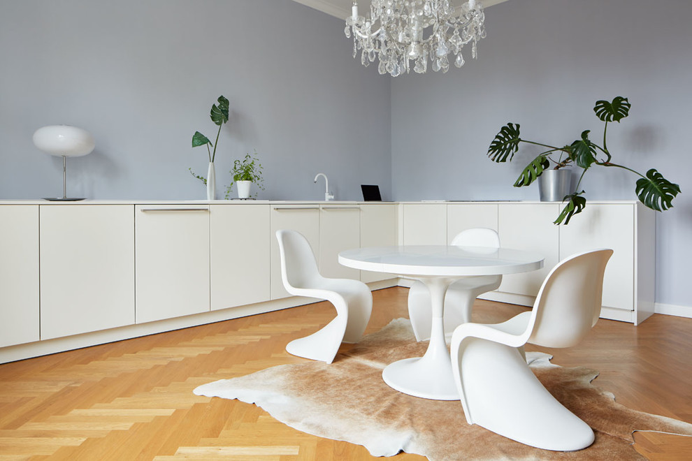 Mittelgroße Moderne Wohnküche mit blauer Wandfarbe und braunem Holzboden in Köln