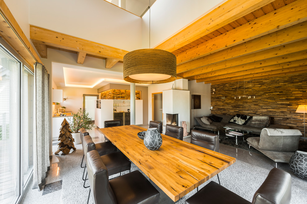 Esempio di una grande sala da pranzo aperta verso il soggiorno contemporanea con pareti bianche, stufa a legna, cornice del camino in intonaco e pavimento grigio