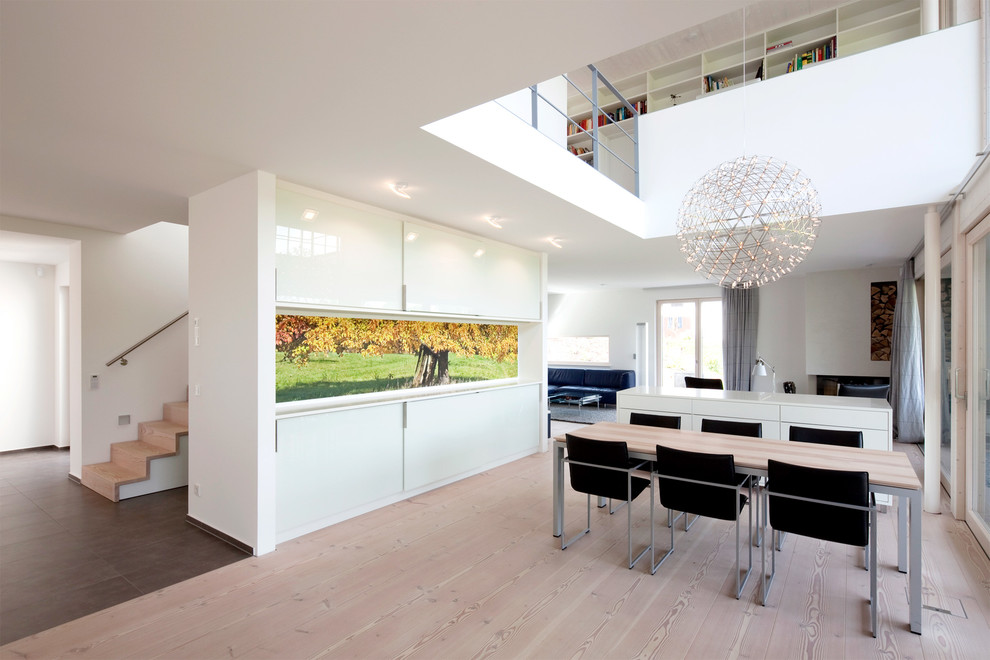 Imagen de comedor actual grande abierto con paredes blancas y suelo de madera clara