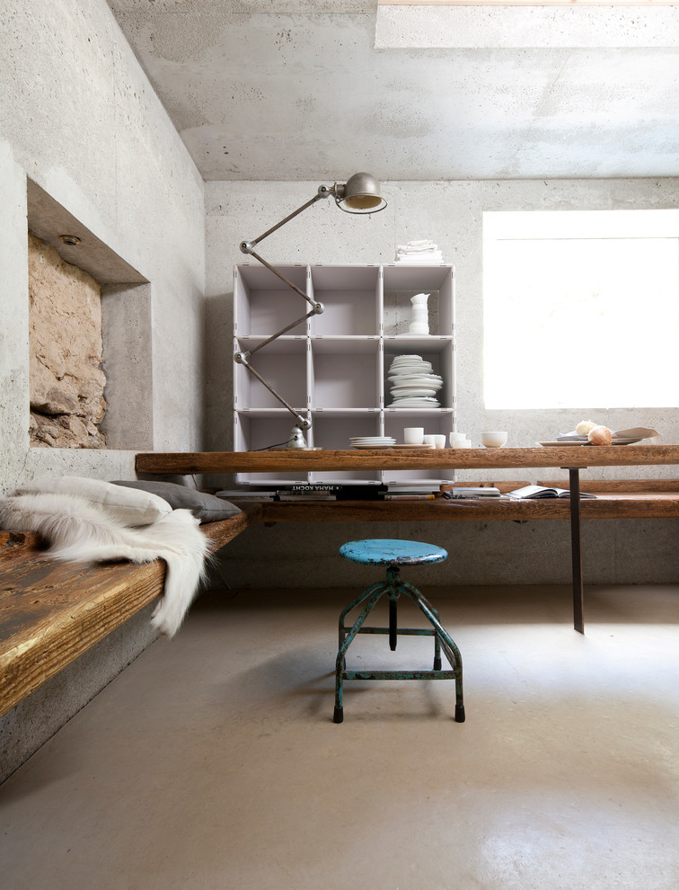 Aménagement d'une salle à manger industrielle avec un mur gris et sol en béton ciré.