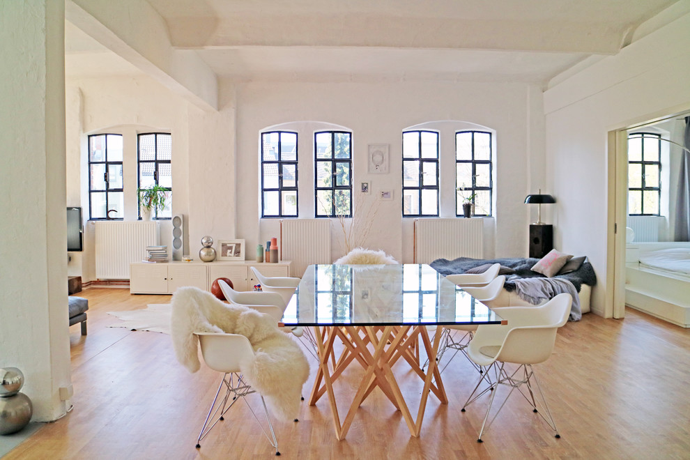 Expansive bohemian open plan dining room in Hamburg with white walls and light hardwood flooring.