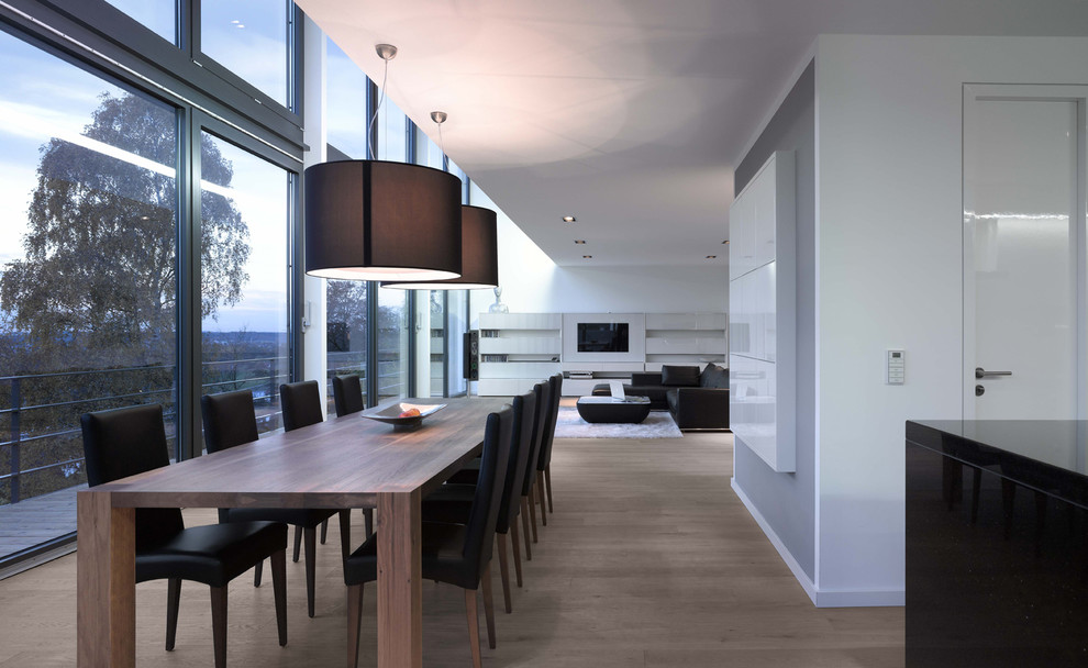 Immagine di una grande sala da pranzo aperta verso il soggiorno minimal con pareti bianche e pavimento in legno massello medio