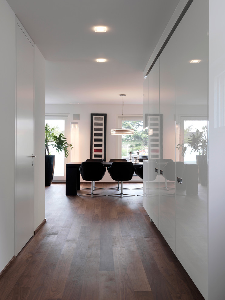 На фото: столовая среднего размера в стиле модернизм с белыми стенами и темным паркетным полом с