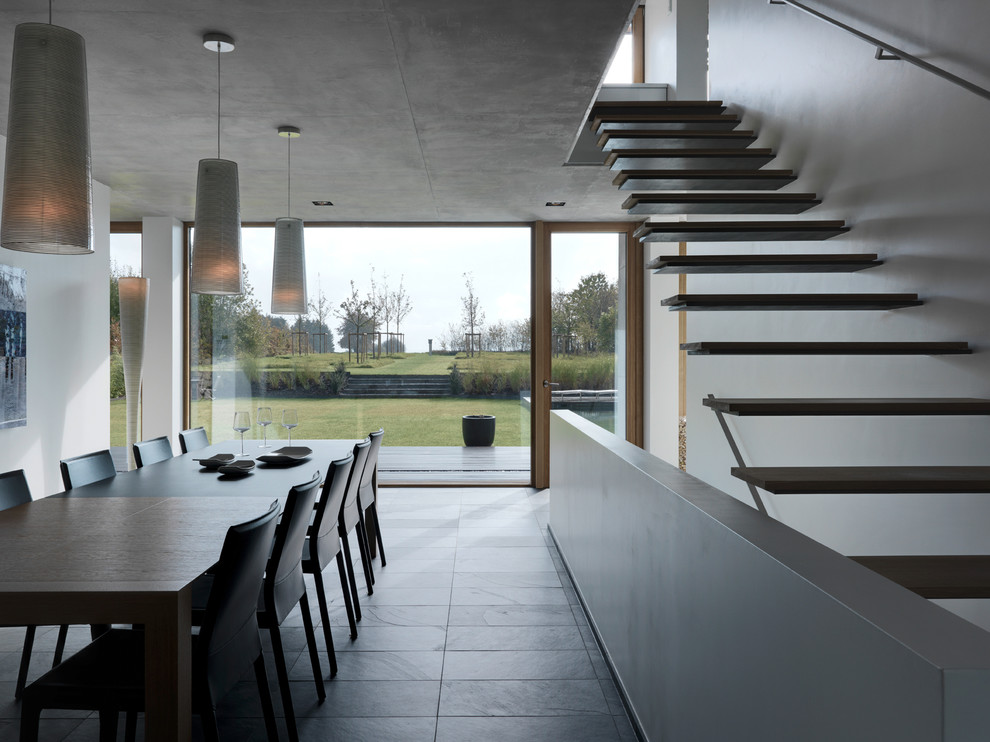 Ispirazione per una sala da pranzo aperta verso il soggiorno minimalista di medie dimensioni con pareti bianche e pavimento in ardesia