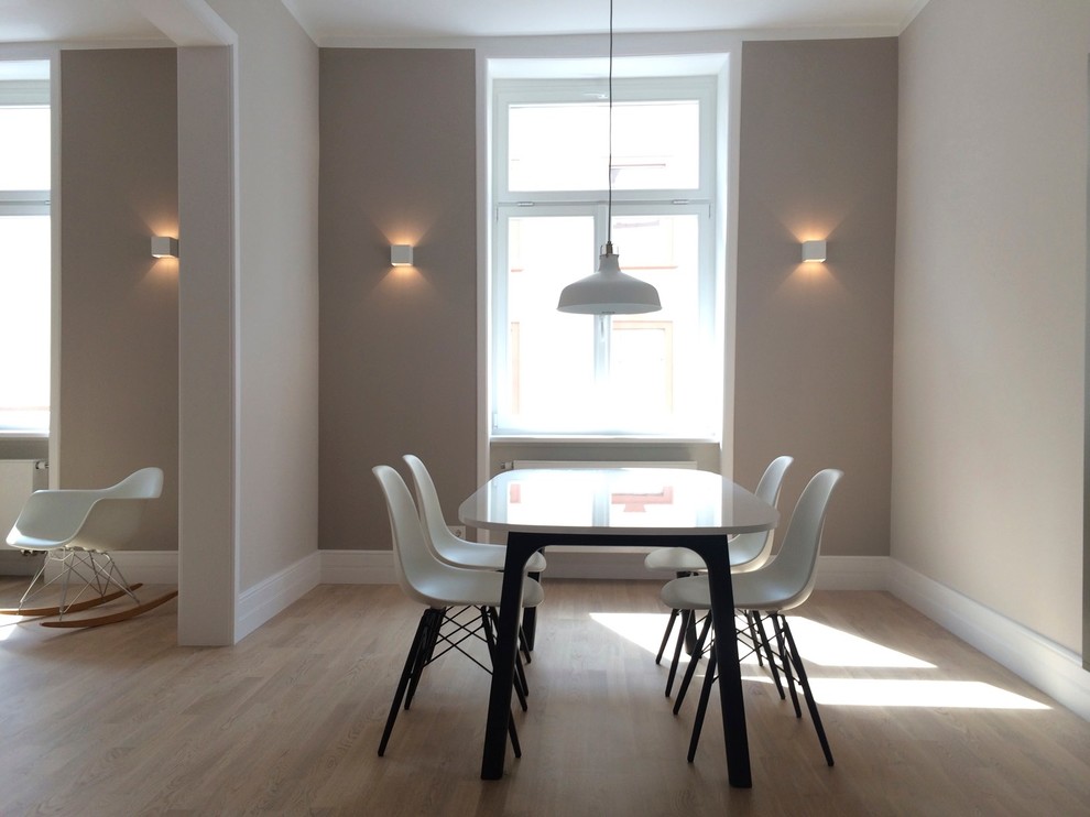 Cette image montre une salle à manger ouverte sur le salon design de taille moyenne avec un mur beige, un sol en bois brun et aucune cheminée.