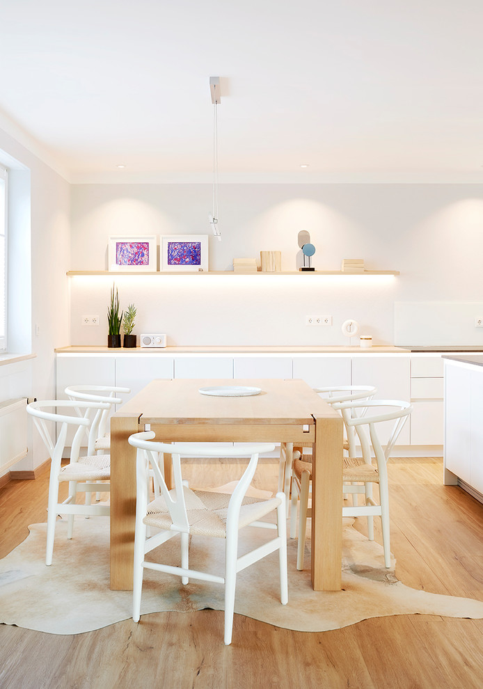 Example of a danish medium tone wood floor and brown floor kitchen/dining room combo design in Munich with white walls and no fireplace