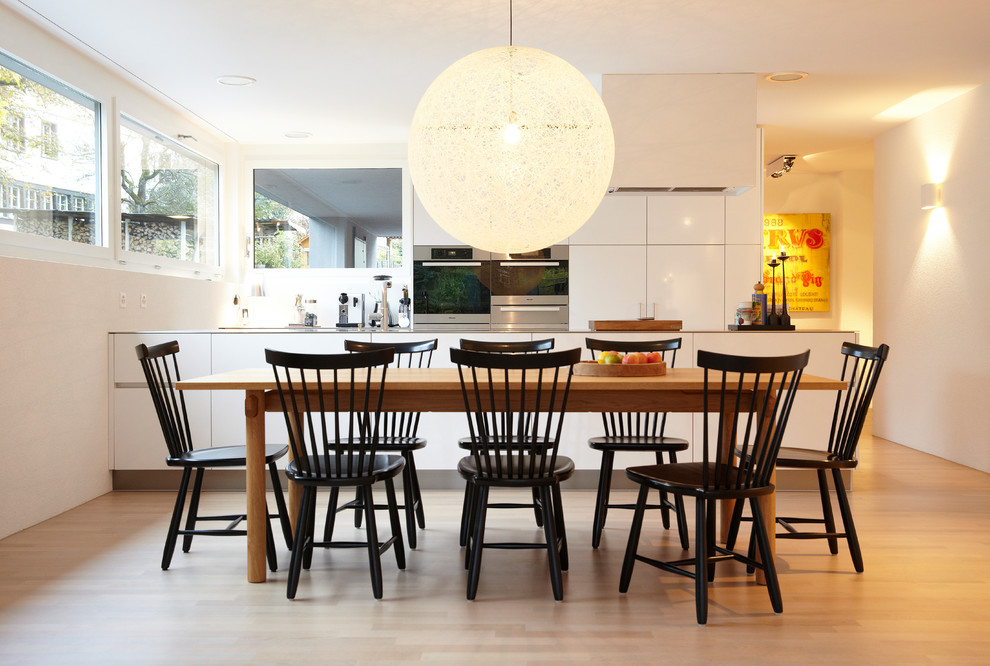Mittelgroße Moderne Wohnküche ohne Kamin mit weißer Wandfarbe, hellem Holzboden und braunem Boden in Hamburg