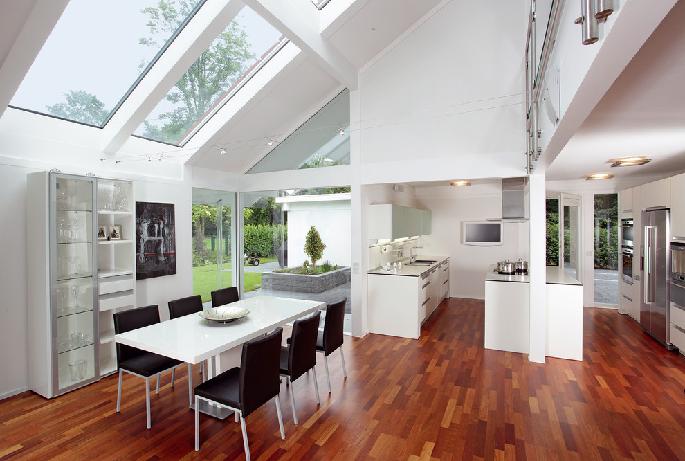 Exemple d'une grande salle à manger ouverte sur le salon tendance avec un mur blanc, un sol en bois brun et un sol marron.