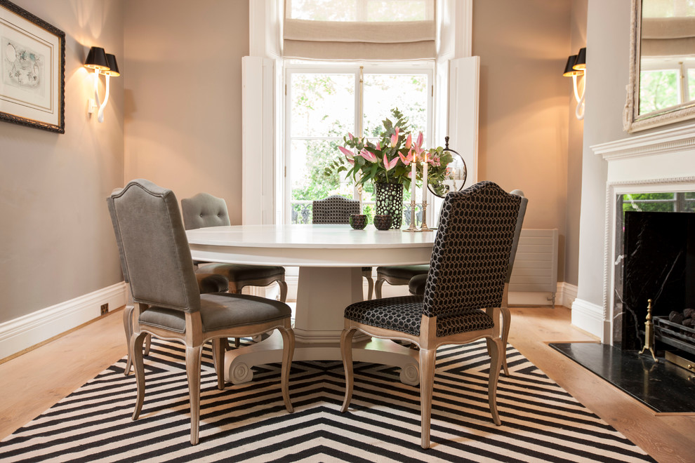 На фото: столовая в классическом стиле с серыми стенами, стандартным камином и светлым паркетным полом
