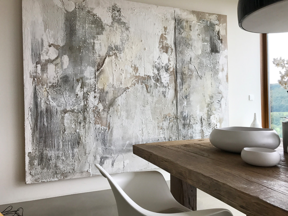 Cette image montre une très grande salle à manger ouverte sur le salon minimaliste avec un mur blanc, sol en béton ciré, aucune cheminée et un sol gris.