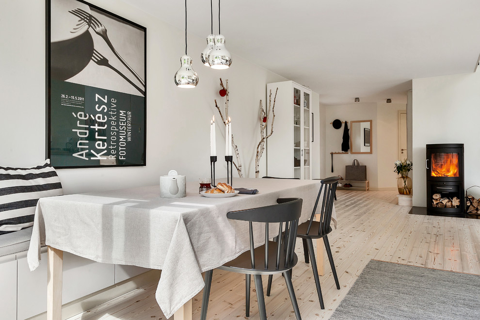 Exemple d'une salle à manger ouverte sur le salon scandinave de taille moyenne avec un mur blanc, parquet clair et un poêle à bois.