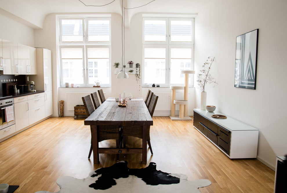 Mittelgroßes Skandinavisches Esszimmer mit weißer Wandfarbe und braunem Holzboden in Berlin