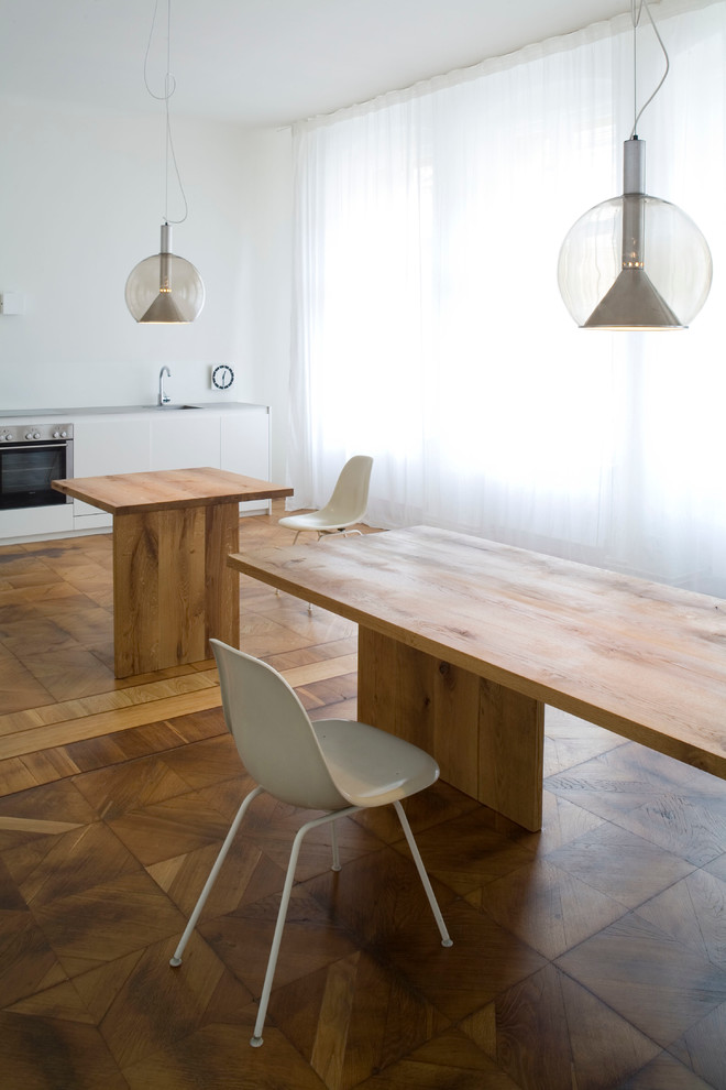 Cette image montre une salle à manger design de taille moyenne avec un mur blanc et un sol en bois brun.