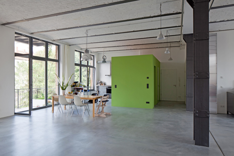 Großes Industrial Esszimmer mit grüner Wandfarbe und Betonboden in Berlin