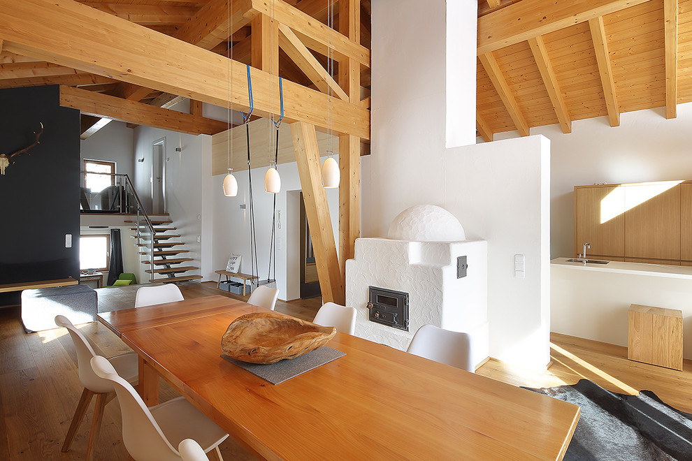 Cette photo montre une salle à manger ouverte sur le salon nature avec un mur blanc, parquet clair, une cheminée standard, un manteau de cheminée en plâtre et un sol beige.