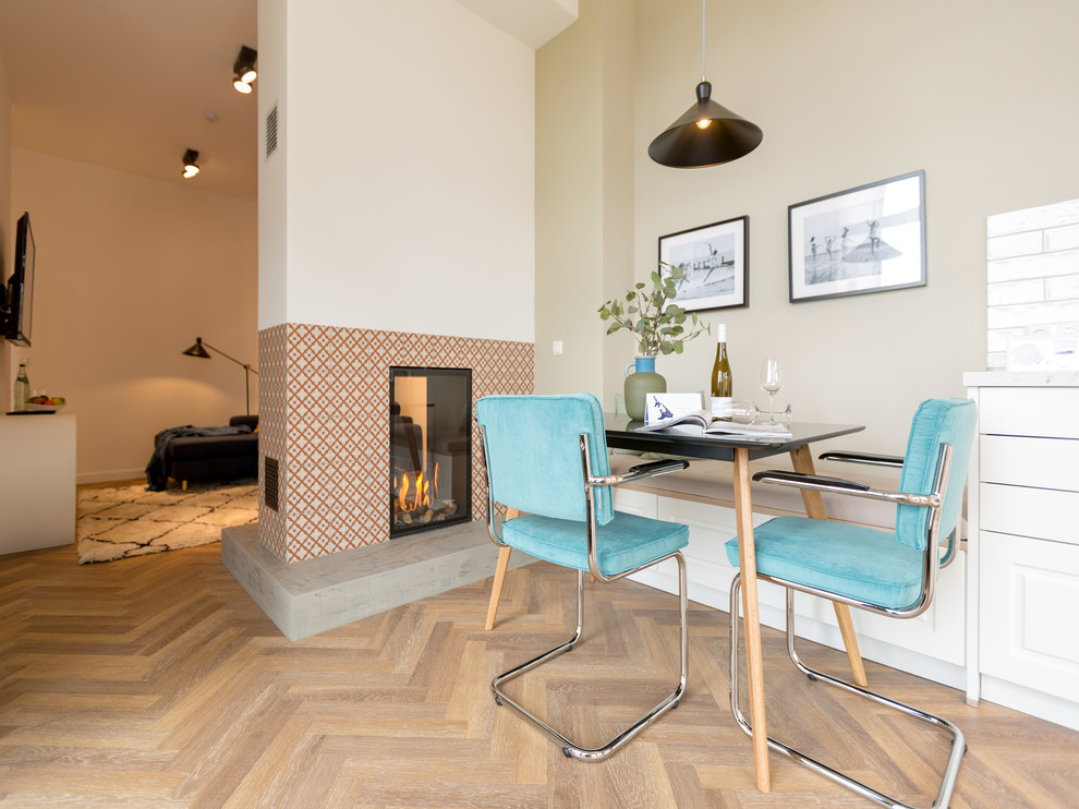 Mittelgroße Moderne Wohnküche mit Tunnelkamin, gefliester Kaminumrandung, beiger Wandfarbe, braunem Holzboden und braunem Boden in Berlin