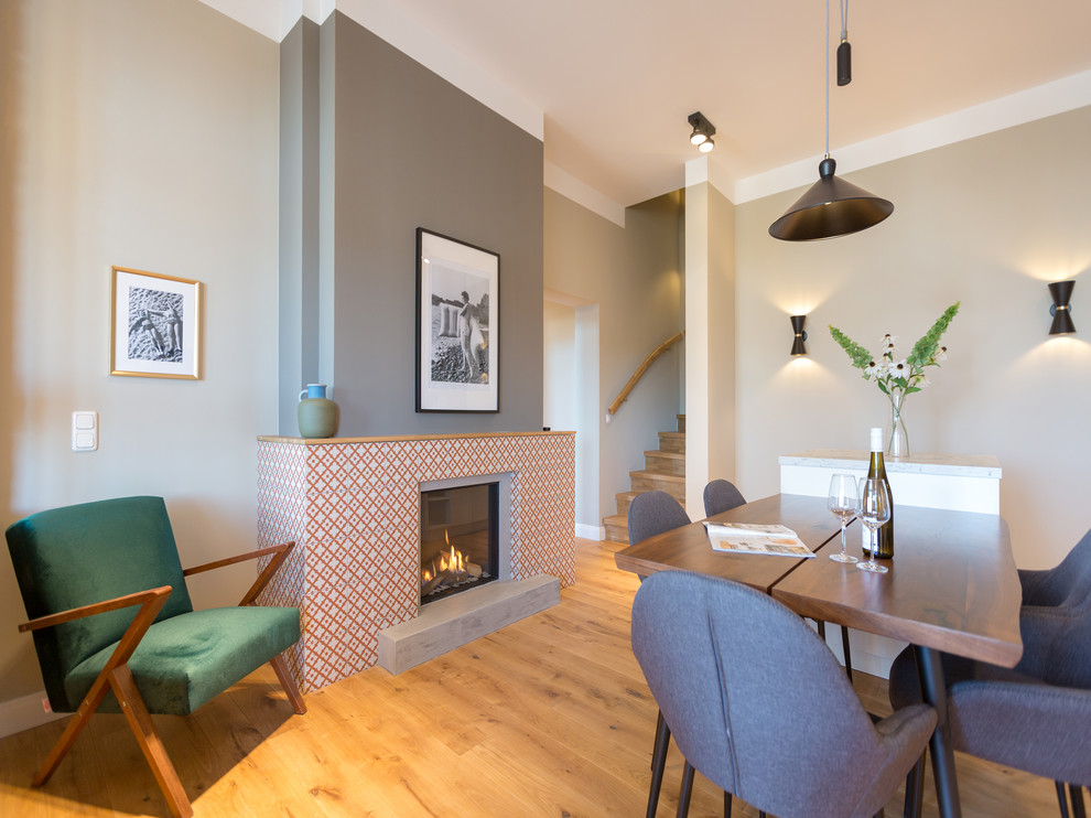 Aménagement d'une salle à manger contemporaine fermée et de taille moyenne avec une cheminée standard, un manteau de cheminée en carrelage, un mur marron, un sol en bois brun et un sol marron.