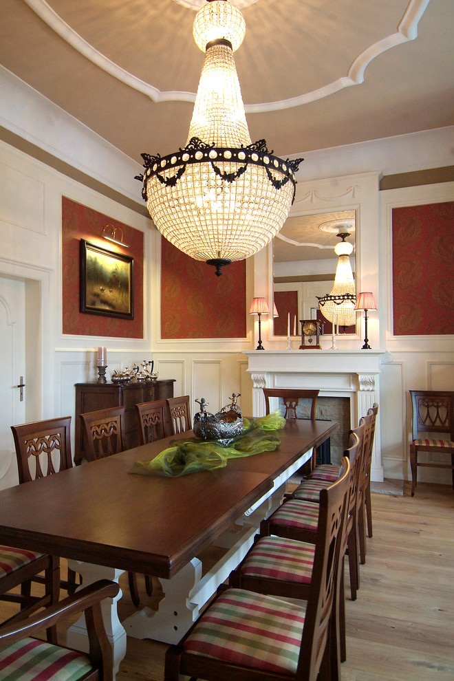 Esempio di una grande sala da pranzo classica con pareti rosse, parquet chiaro, stufa a legna e cornice del camino in legno